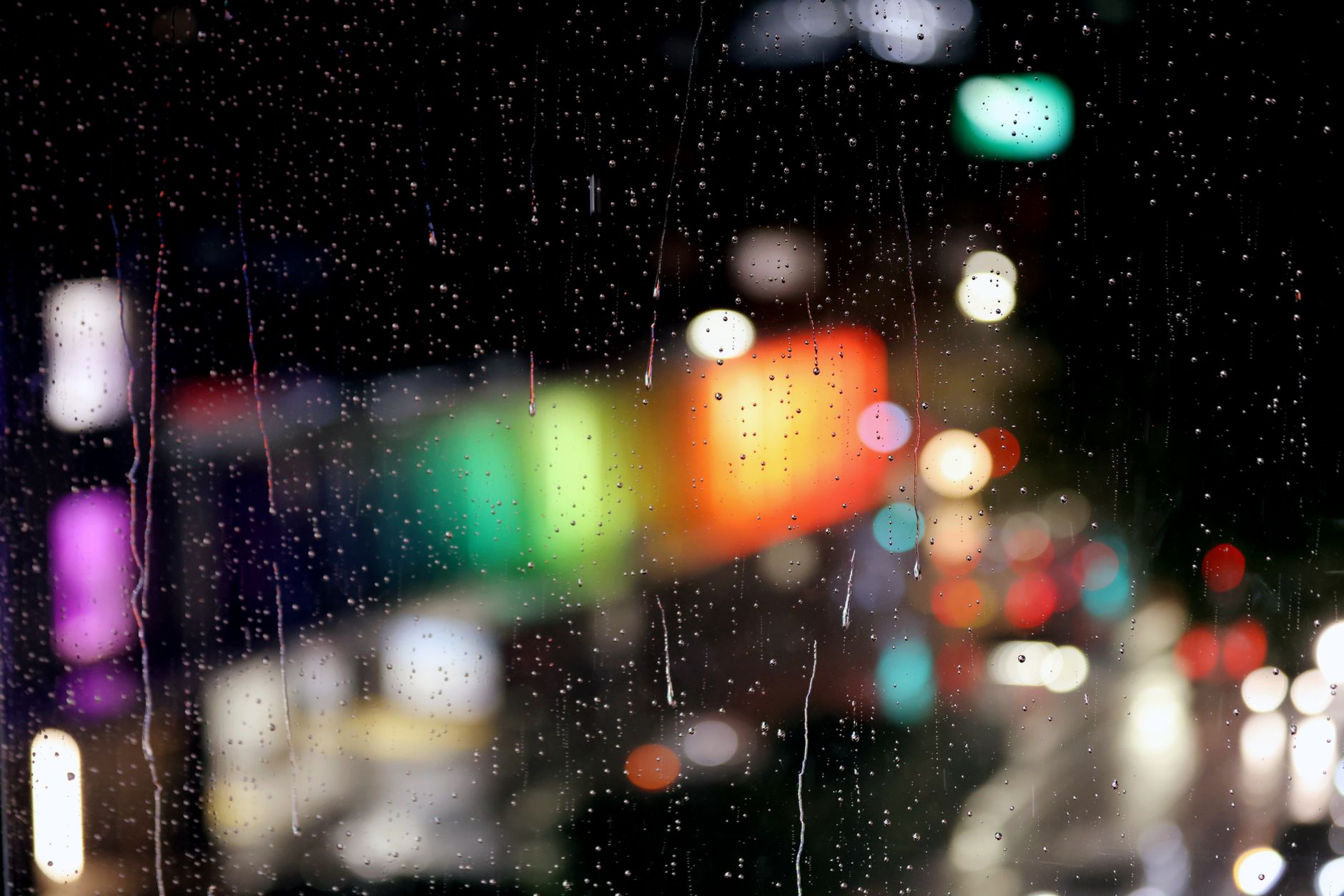雨の窓越しににじむ色鮮やかな都市の光