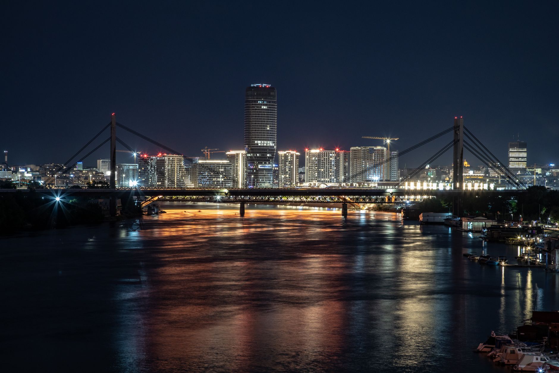 夜にライトアップされた美しい吊り橋と都市のビル群