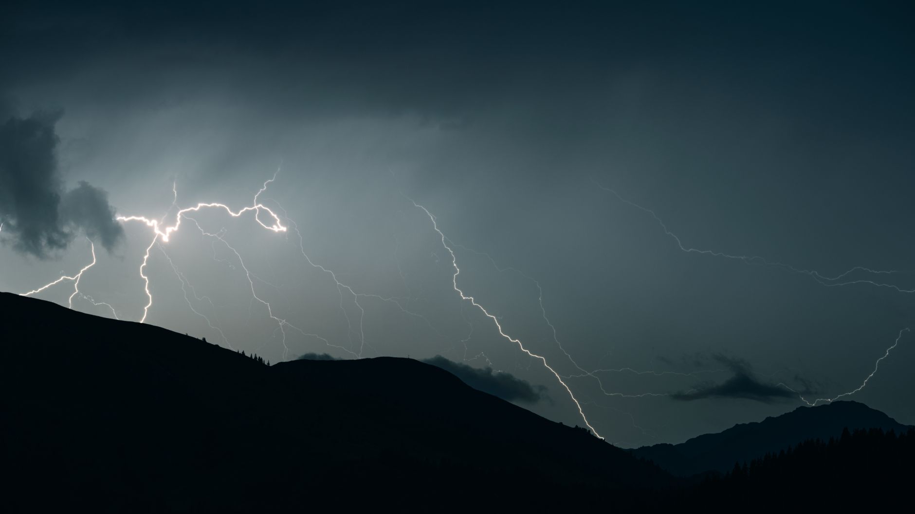 暗雲立ち込める山々に光る激しい稲妻